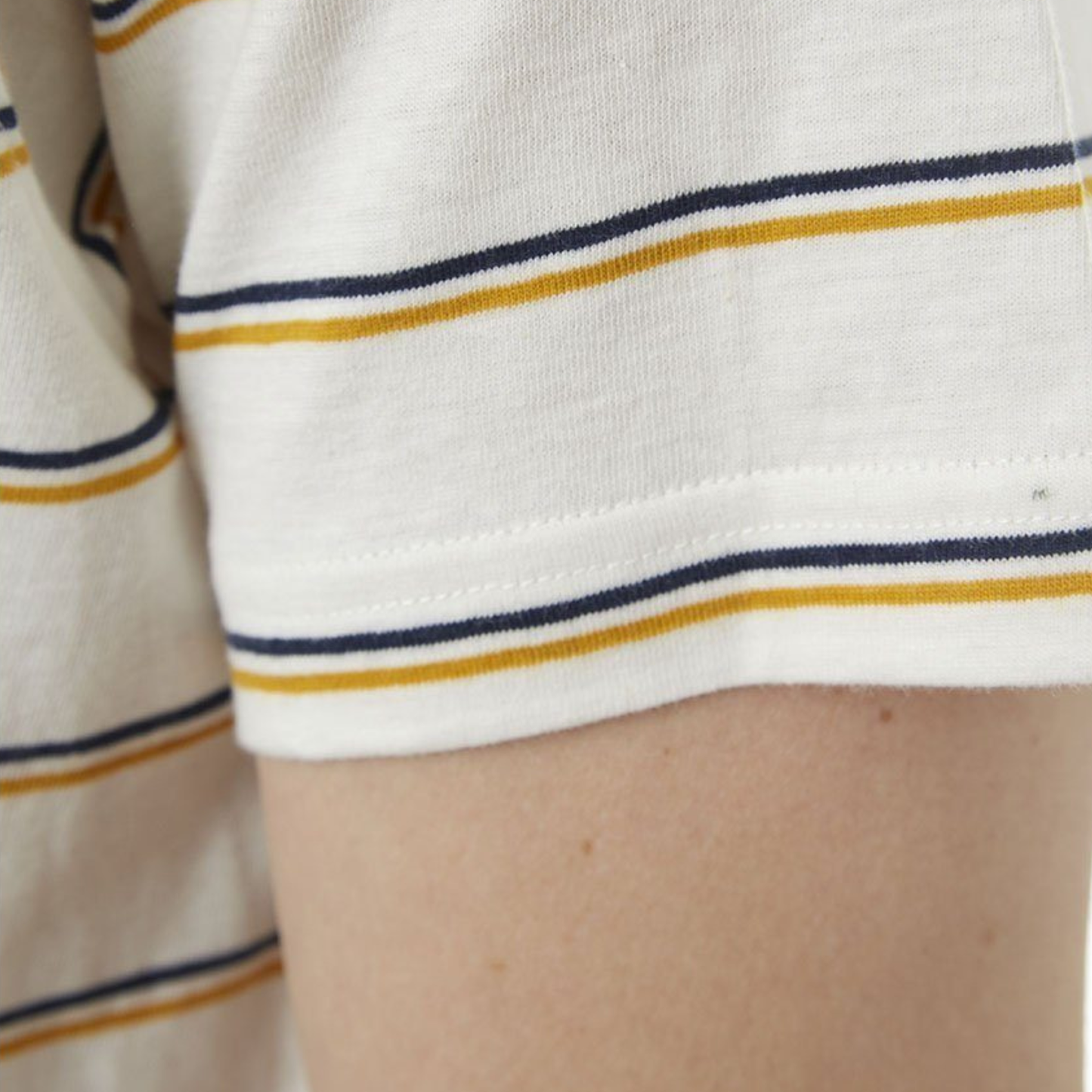 Close-up of a white shirt with blue and yellow stripes on a person's arm.