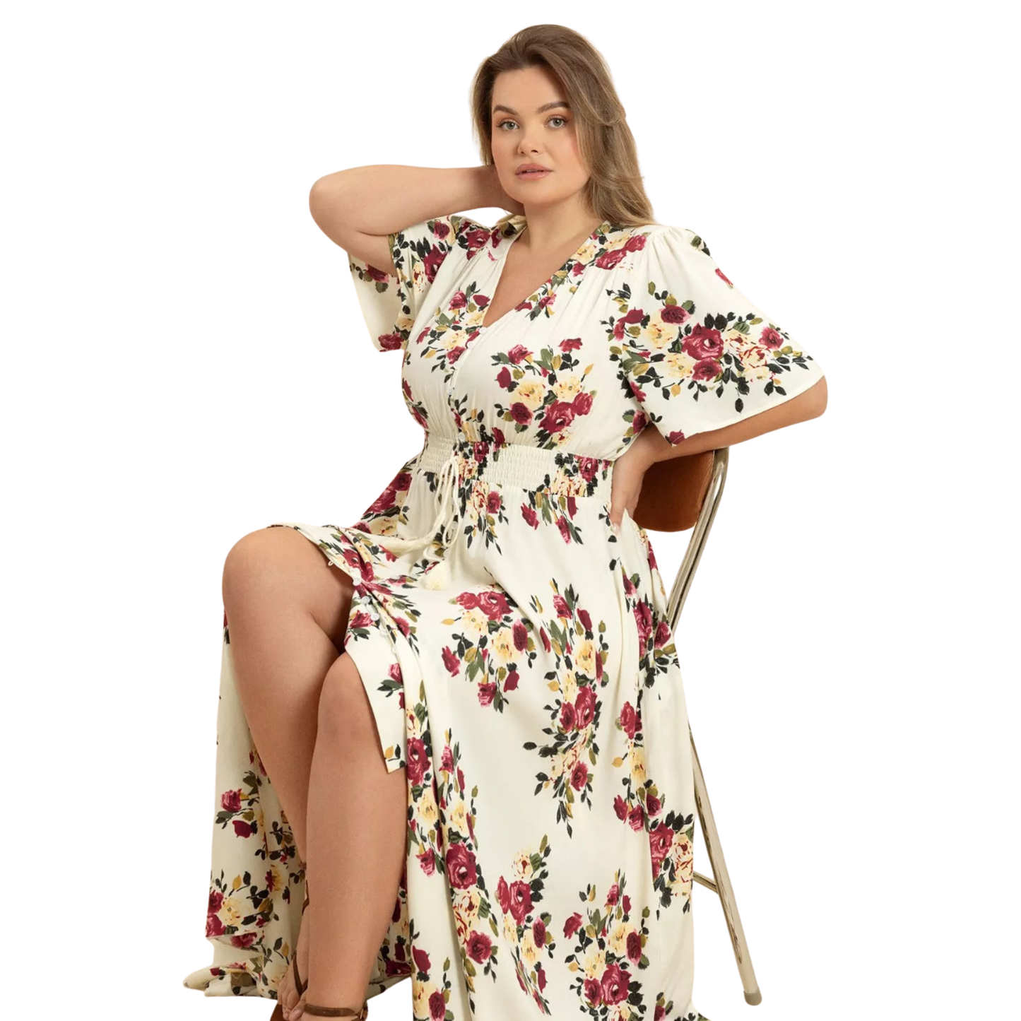 Woman wearing a floral dress sitting on a chair against a white background