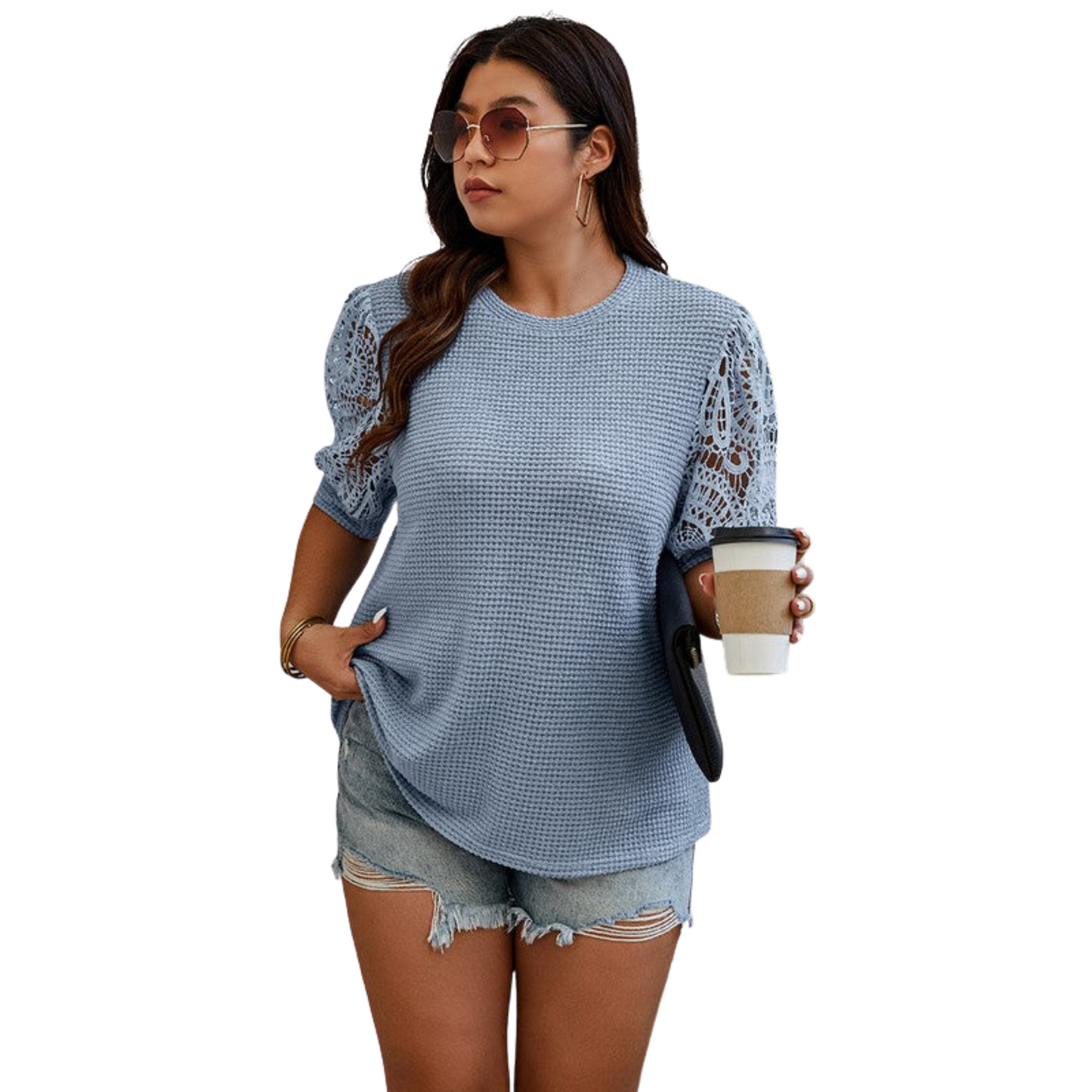 Woman wearing a blue textured top with lace sleeves and denim shorts, holding a coffee cup.