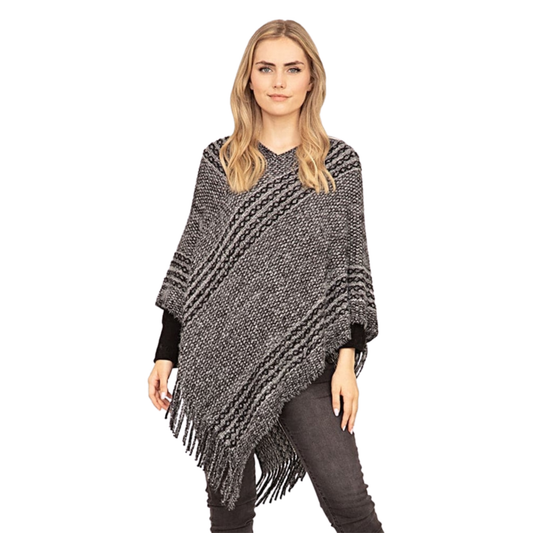 Woman wearing a gray knitted poncho with fringe on a white background
