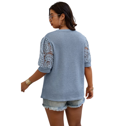 Woman wearing a blue textured top with lace sleeves on a white background